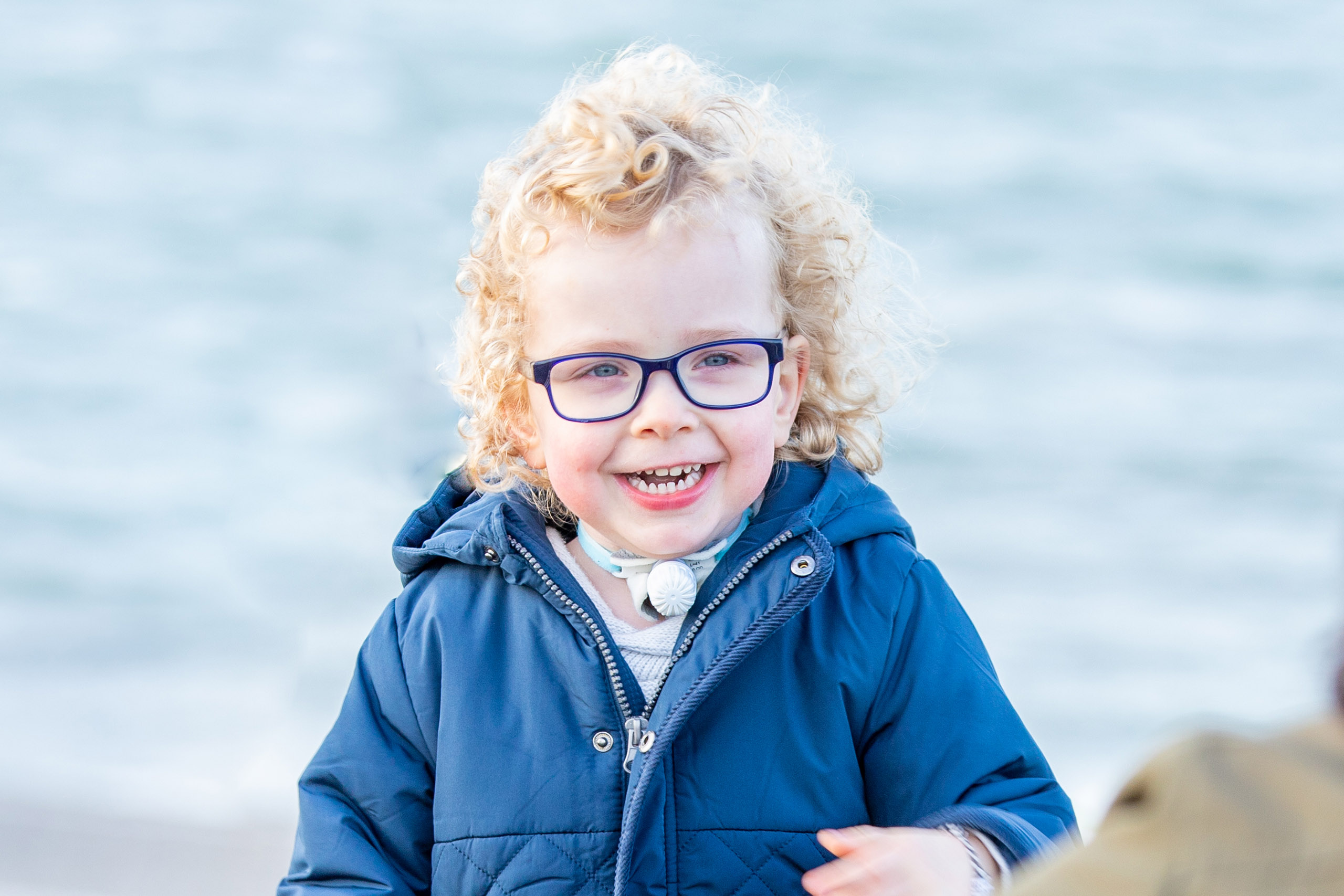 little-boy-with-a-tracheostomy-wearing-xtracaremini-playing-on-the-beach